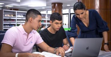Estudiantes y Profesora de Economía revisando el computador