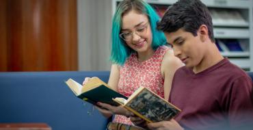 Estudiantes leyendo libros en la biblioteca de la universidad