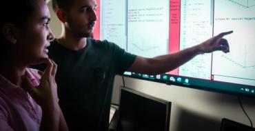 Estudiantes de matemáticas revisando datos y algortimos en pantalla gigante