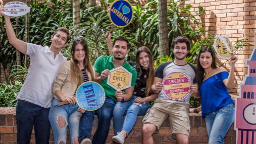 Movilidad internacional en la Javeriana Cali Grupo de estudiantes con carteles de diferentes países y mensajes positivos