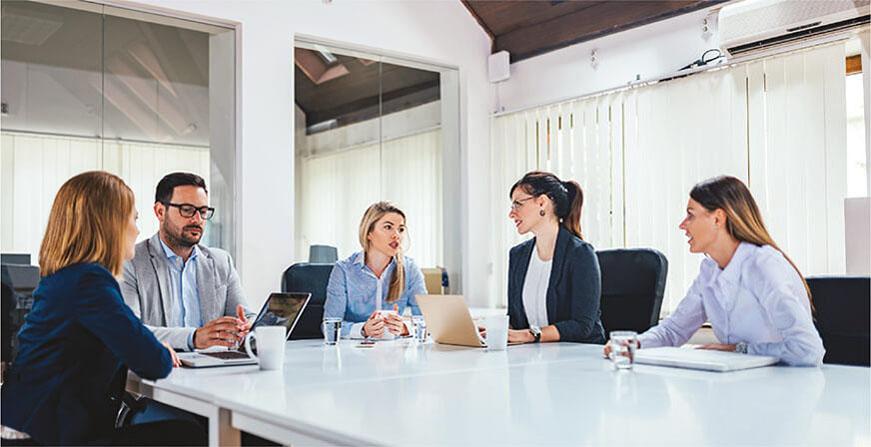 Especialización en Finanzas Grupo de personas en reunión revisando sus computadores