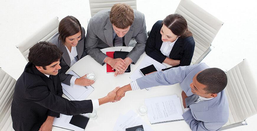Especialización en Negocios Internacionales Grupo de personas cerrando un negocio en mesa redonda
