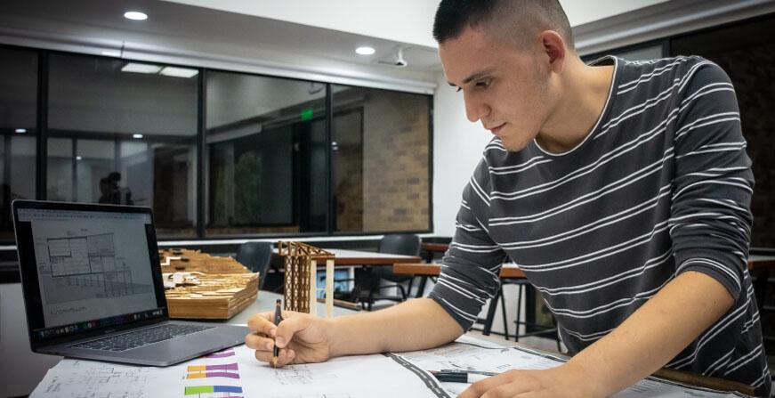 Estudiante de Arquitectura Estudiante con plano y computador en un salón