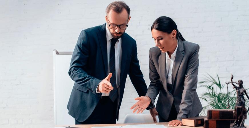 Especialización en Derecho Comercial Mujer y Hombre conversando y revisando documentos