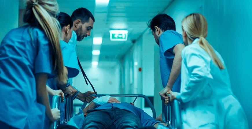 Especialización en Medicina de Urgencias Grupo de médicos y enfermeros traslando a un paciente en una camilla