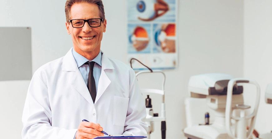Especialización en Oftalmología oftalmólogo sonriendo en su consultorio