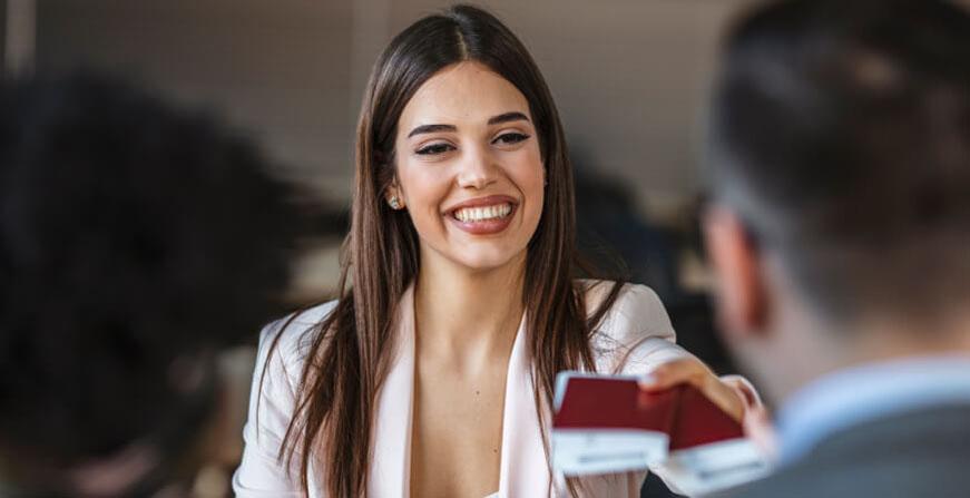 Turismo de la Javeriana Cali Joven mujer entregando pasaporte a un cliente